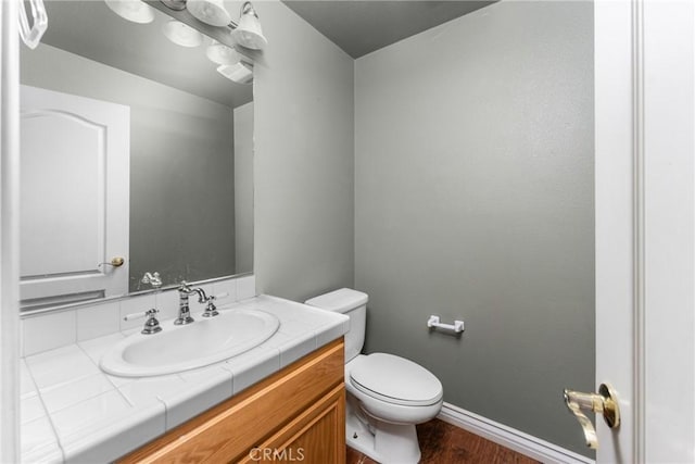 bathroom featuring toilet, wood-type flooring, and vanity