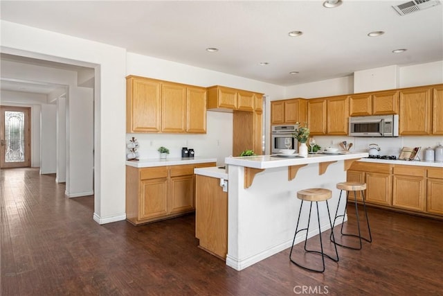 kitchen featuring a kitchen breakfast bar, dark hardwood / wood-style flooring, stainless steel appliances, and a kitchen island