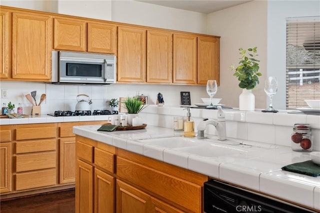 kitchen with decorative backsplash, dark wood-type flooring, gas stovetop, dishwasher, and sink