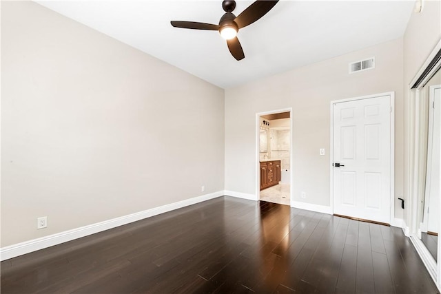 unfurnished bedroom featuring ensuite bathroom, ceiling fan, dark hardwood / wood-style flooring, and a closet