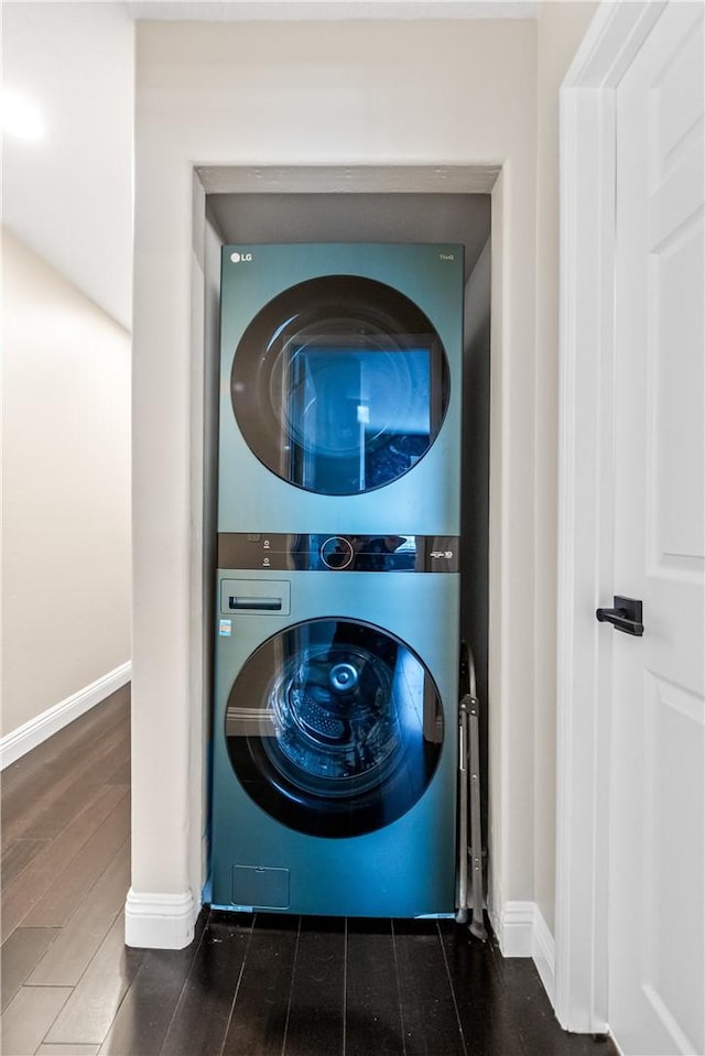 laundry room with stacked washer / drying machine and dark wood-type flooring