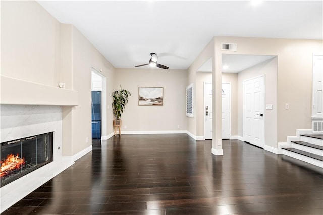 living room with dark wood-type flooring, ceiling fan, and a premium fireplace