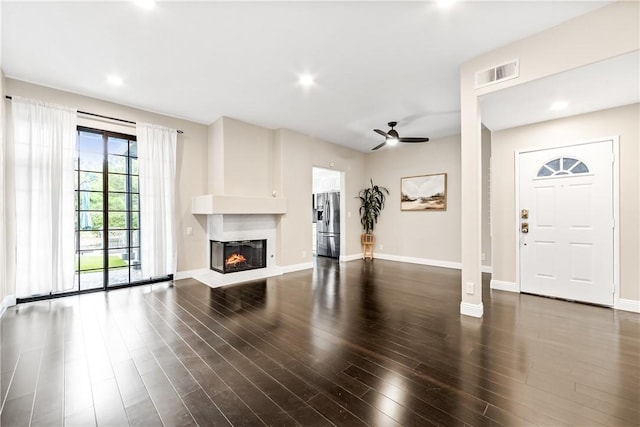 unfurnished living room featuring dark wood-type flooring and ceiling fan