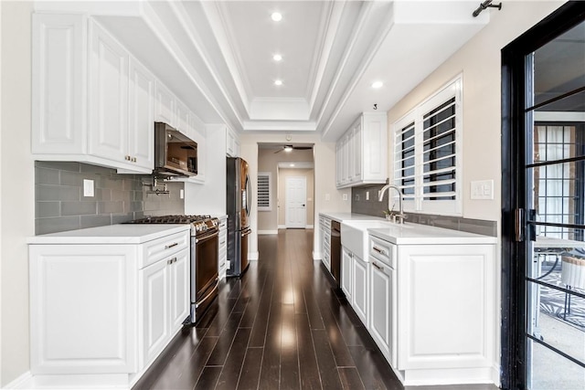 kitchen featuring white cabinets, sink, stainless steel refrigerator, and gas range