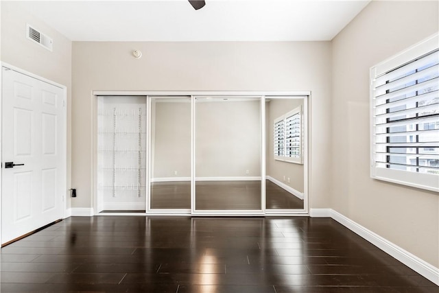 unfurnished bedroom featuring ceiling fan, a closet, and dark hardwood / wood-style flooring