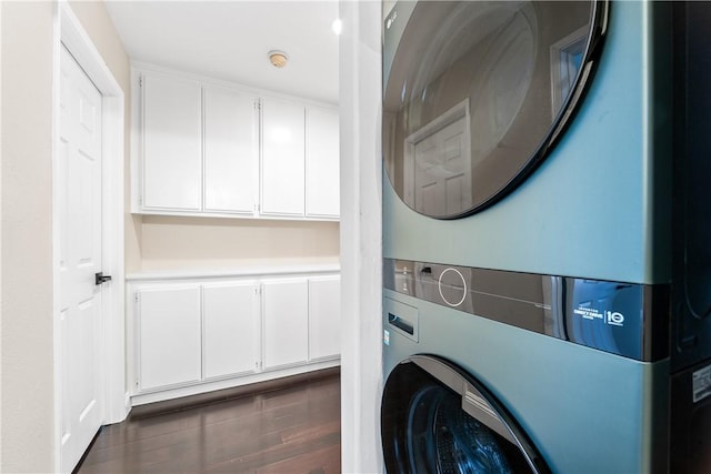 washroom with cabinets, dark wood-type flooring, and stacked washer / dryer