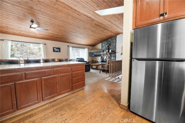 kitchen with tile counters, wood ceiling, stainless steel fridge, light wood-type flooring, and ceiling fan