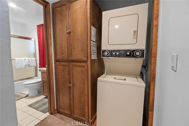 laundry room featuring stacked washer and clothes dryer and light tile patterned flooring