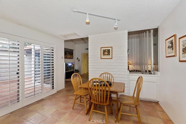 tiled dining space with a textured ceiling and rail lighting