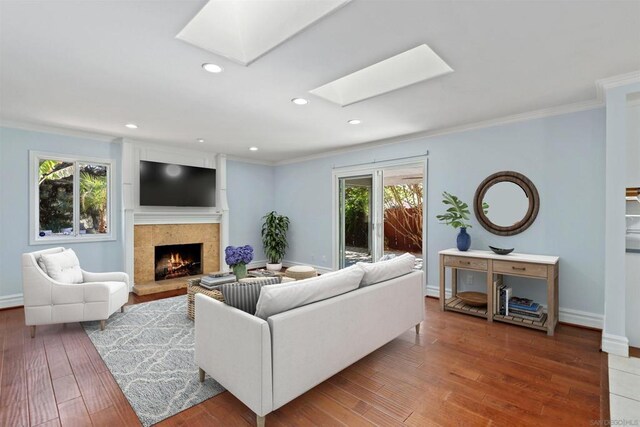 living room with a healthy amount of sunlight, a skylight, a tile fireplace, and ornamental molding