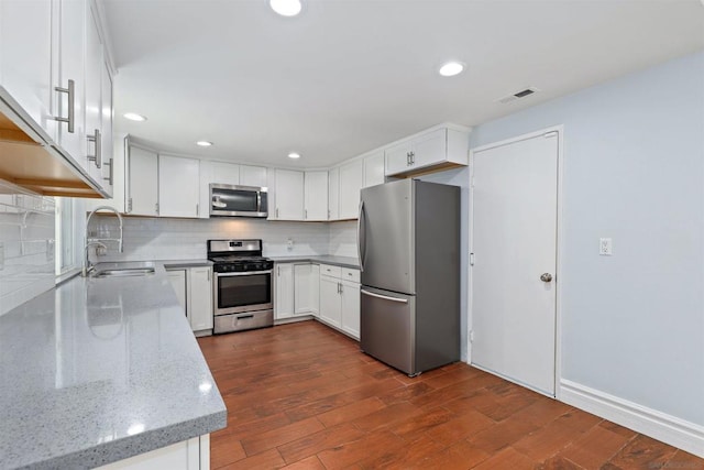 kitchen featuring white cabinetry, appliances with stainless steel finishes, tasteful backsplash, light stone counters, and sink