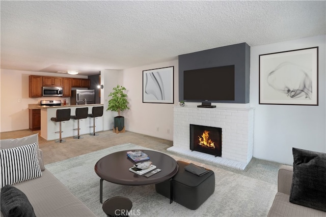 living room featuring a textured ceiling, light carpet, and a fireplace