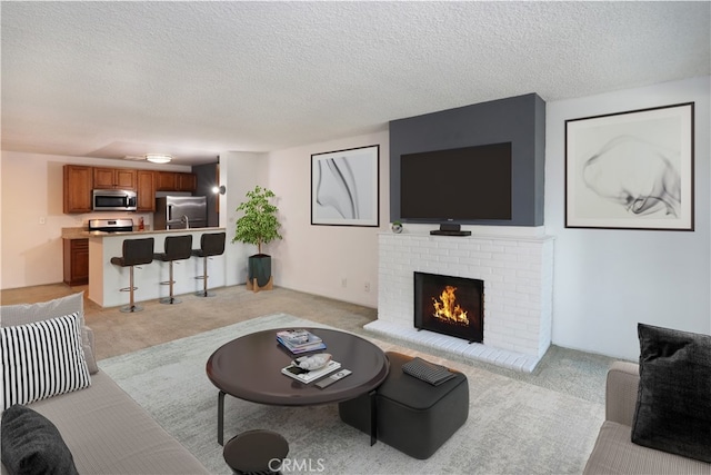 living area featuring a textured ceiling, a fireplace, and light colored carpet