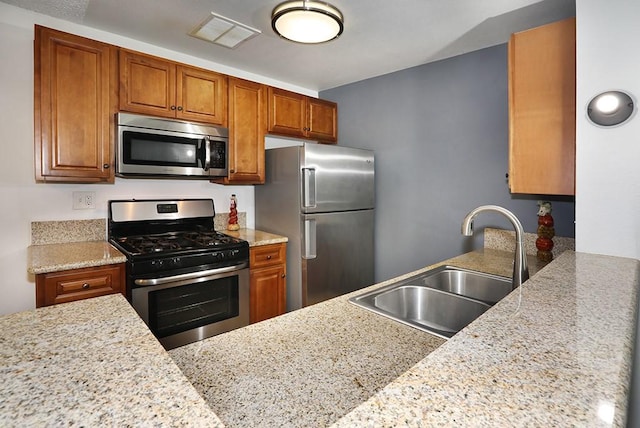 6405 Green Valley Cir Unit 209, Culver City, CA 90230 - kitchen with stainless steel appliances, a sink, brown cabinets, and light stone countertops