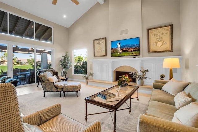 living room with ceiling fan, beam ceiling, and a towering ceiling