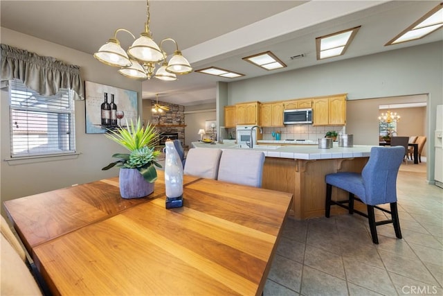 dining room featuring light tile patterned floors, a fireplace, sink, and a chandelier