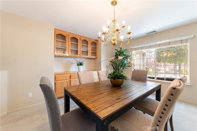 carpeted dining area with a chandelier