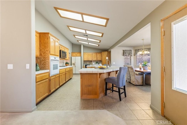 kitchen featuring tile counters, light tile patterned floors, a wealth of natural light, and white appliances