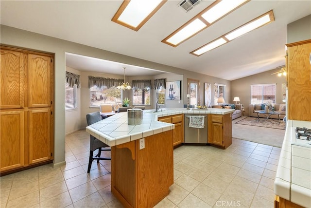 kitchen with lofted ceiling, dishwasher, tile countertops, kitchen peninsula, and hanging light fixtures