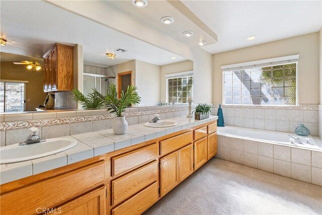 bathroom featuring tasteful backsplash, vanity, ceiling fan, and plus walk in shower