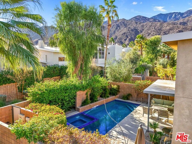 view of pool with a mountain view, a patio, and an in ground hot tub