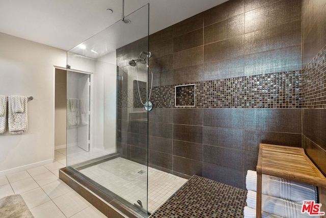 bathroom with tile patterned flooring and a tile shower