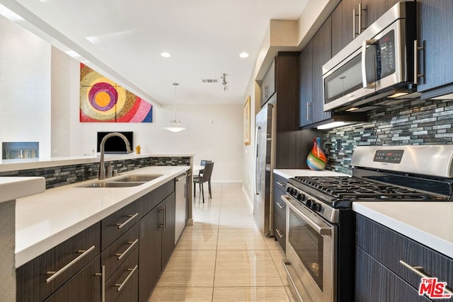 kitchen featuring pendant lighting, sink, appliances with stainless steel finishes, backsplash, and dark brown cabinets