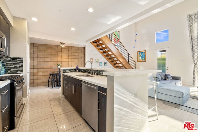 kitchen featuring dark brown cabinetry, stainless steel appliances, sink, and a center island with sink