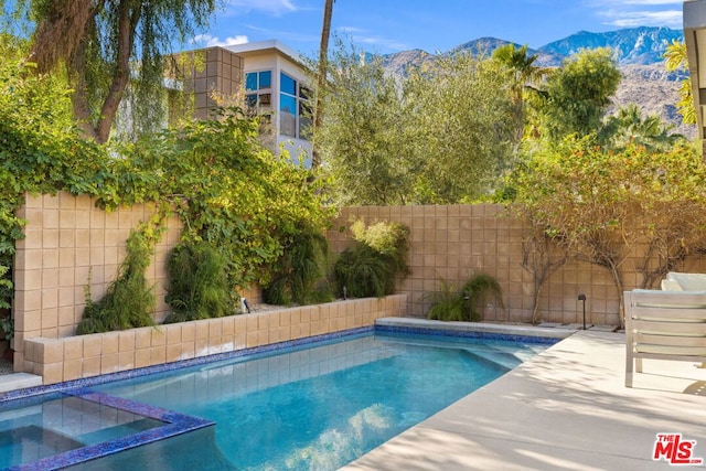 view of swimming pool with an in ground hot tub and a mountain view