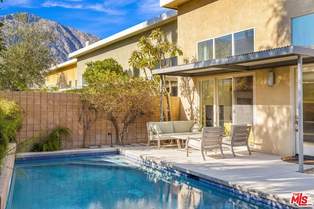 view of pool featuring an outdoor living space, a mountain view, and a patio area