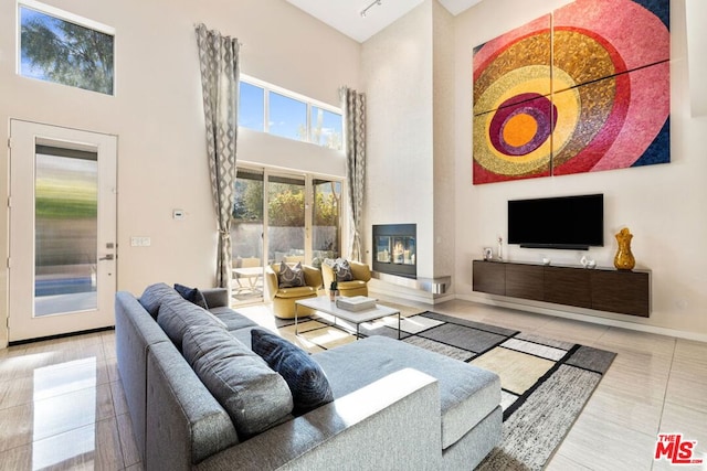 tiled living room featuring a fireplace and a high ceiling