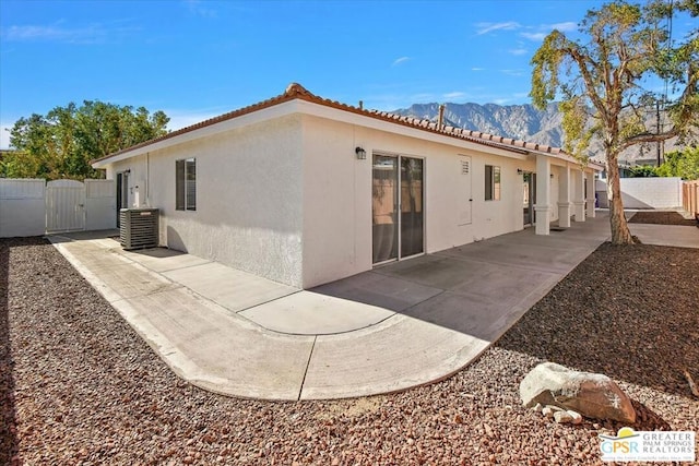 back of house with a mountain view, central AC, and a patio