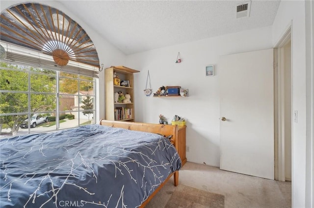 bedroom with visible vents, carpet floors, and a textured ceiling