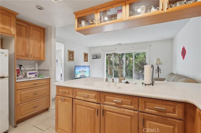 kitchen featuring white refrigerator, light tile patterned flooring, and sink