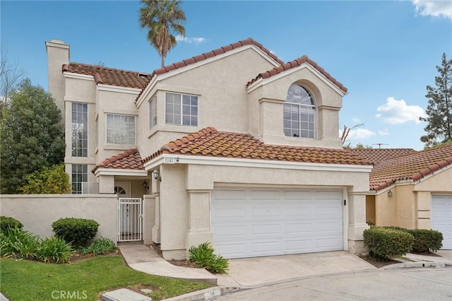 mediterranean / spanish-style house with a gate, a tile roof, driveway, a garage, and stucco siding