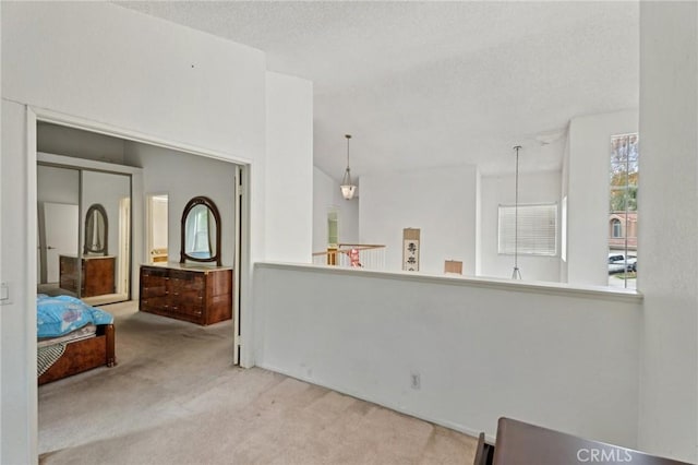 interior space with pendant lighting, light colored carpet, and a textured ceiling