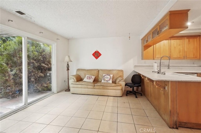 unfurnished living room featuring sink, a textured ceiling, and light tile patterned flooring