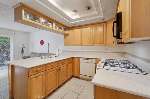 kitchen featuring sink, white dishwasher, a tray ceiling, light tile patterned flooring, and kitchen peninsula