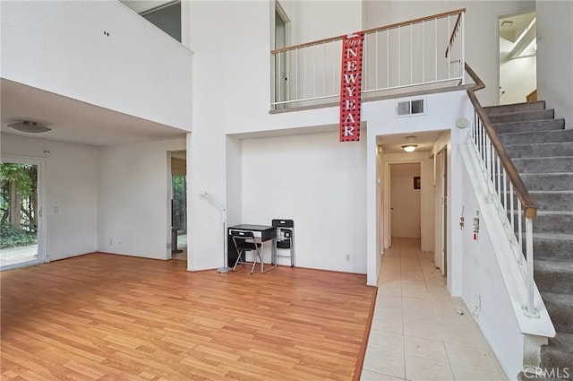 staircase with wood-type flooring and a high ceiling