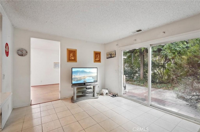 unfurnished living room with visible vents, a textured ceiling, and light tile patterned floors