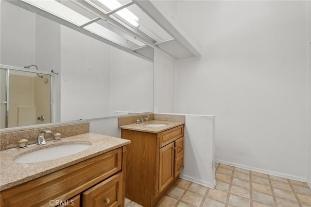 full bathroom featuring two vanities, a shower stall, baseboards, and a sink