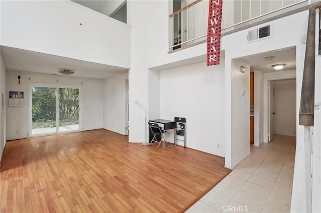 unfurnished living room with light hardwood / wood-style flooring and a high ceiling