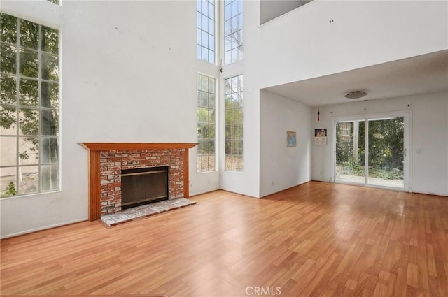 unfurnished living room featuring a brick fireplace, plenty of natural light, and light hardwood / wood-style flooring