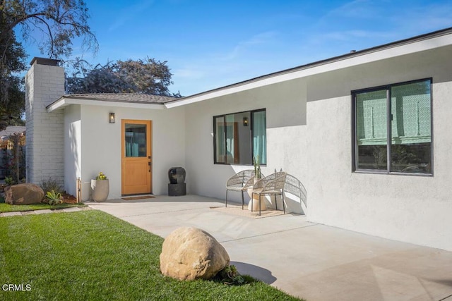 doorway to property with a patio area and a yard