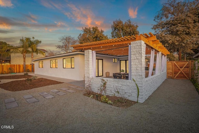 property exterior at dusk featuring a pergola and a patio