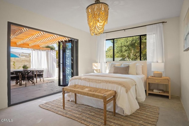 bedroom featuring concrete flooring, access to outside, and a chandelier