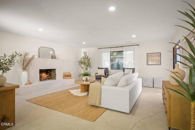 living room featuring finished concrete flooring, a high end fireplace, and recessed lighting