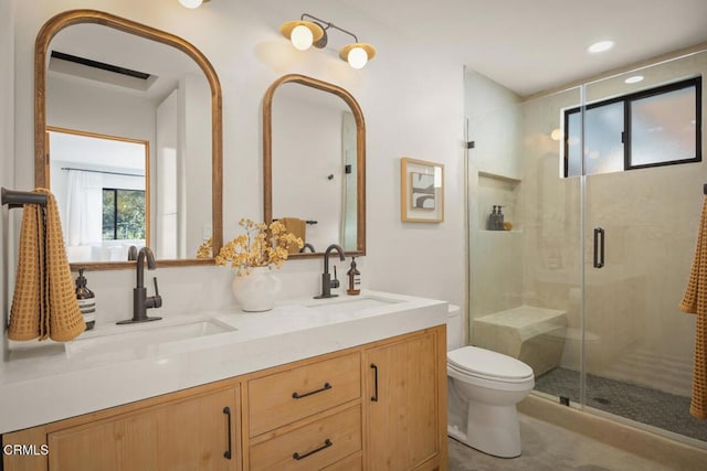 full bath with double vanity, a stall shower, a sink, and toilet