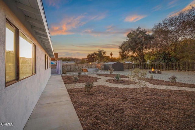 yard at dusk featuring an outbuilding, a patio area, and a fenced backyard