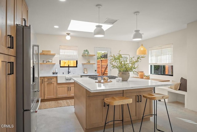 kitchen with a skylight, a sink, a kitchen island, open shelves, and stainless steel fridge